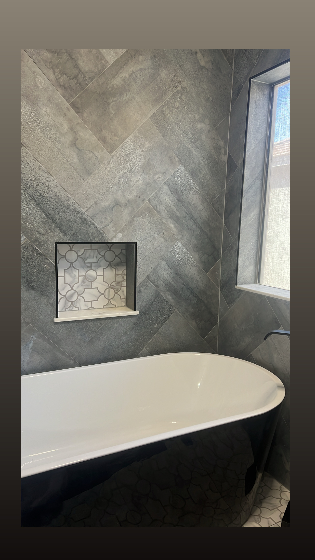Tub with herringbone wall tile and built-in niche by Level Up Tile