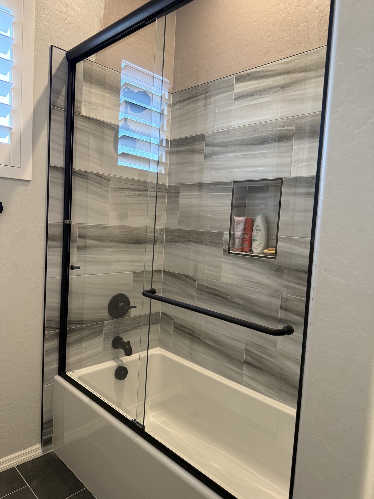 Framed glass shower enclosure with metal trim by Level Up Tile in Peoria AZ