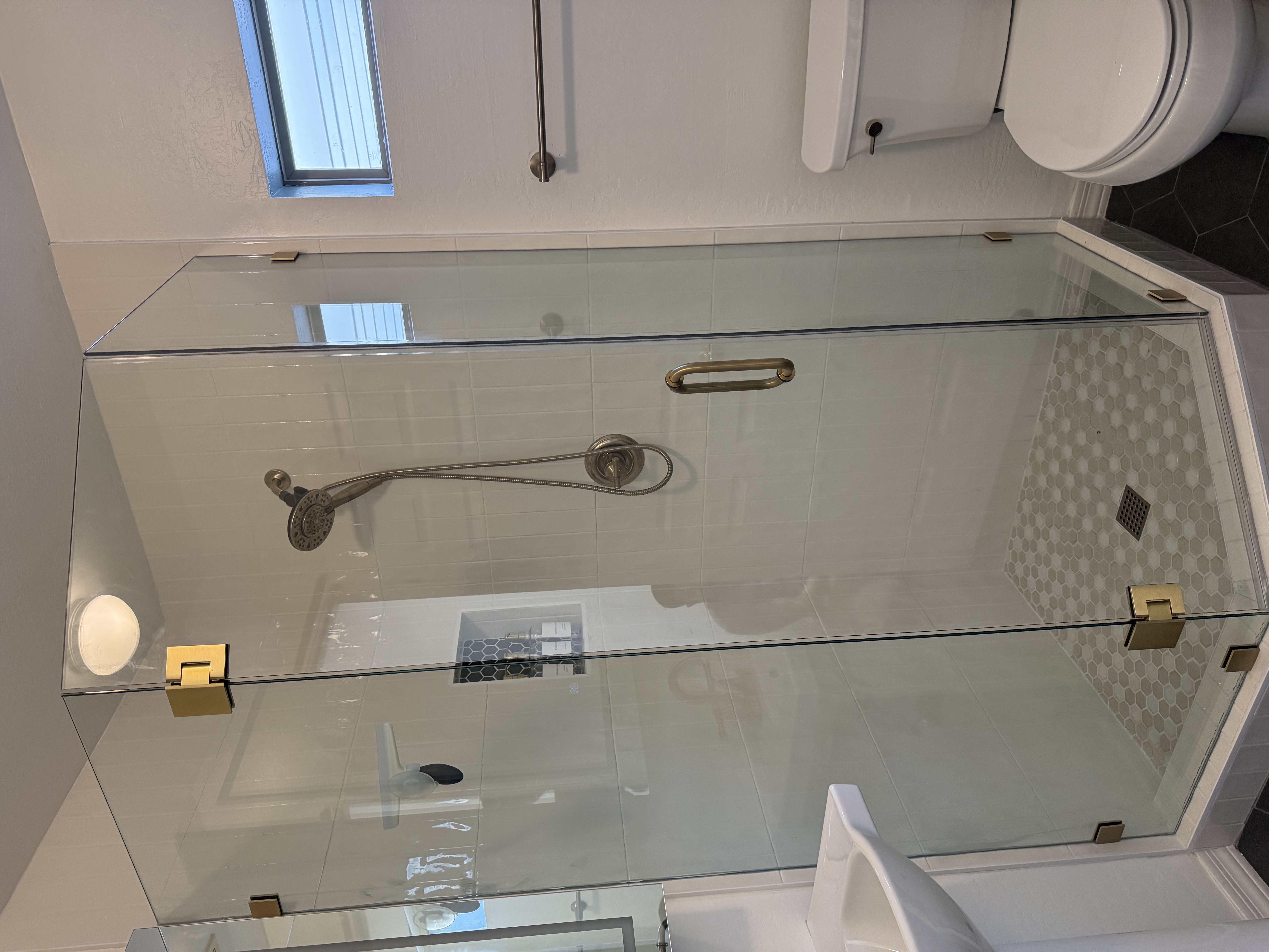 Full bathroom with glass shower enclosure and gold hardware by Level Up Tile