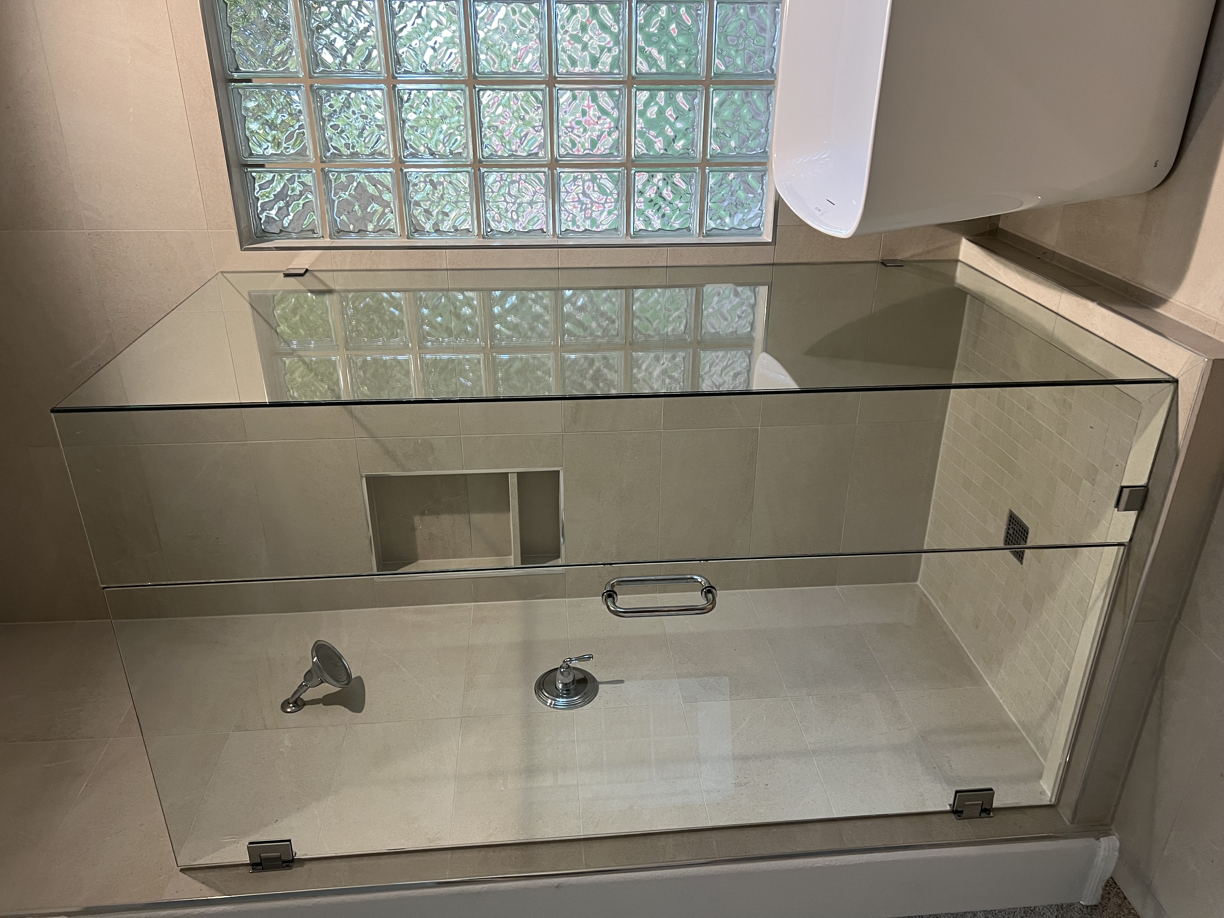 Glass enclosure shower with niche and chrome fixtures by Level Up Tile