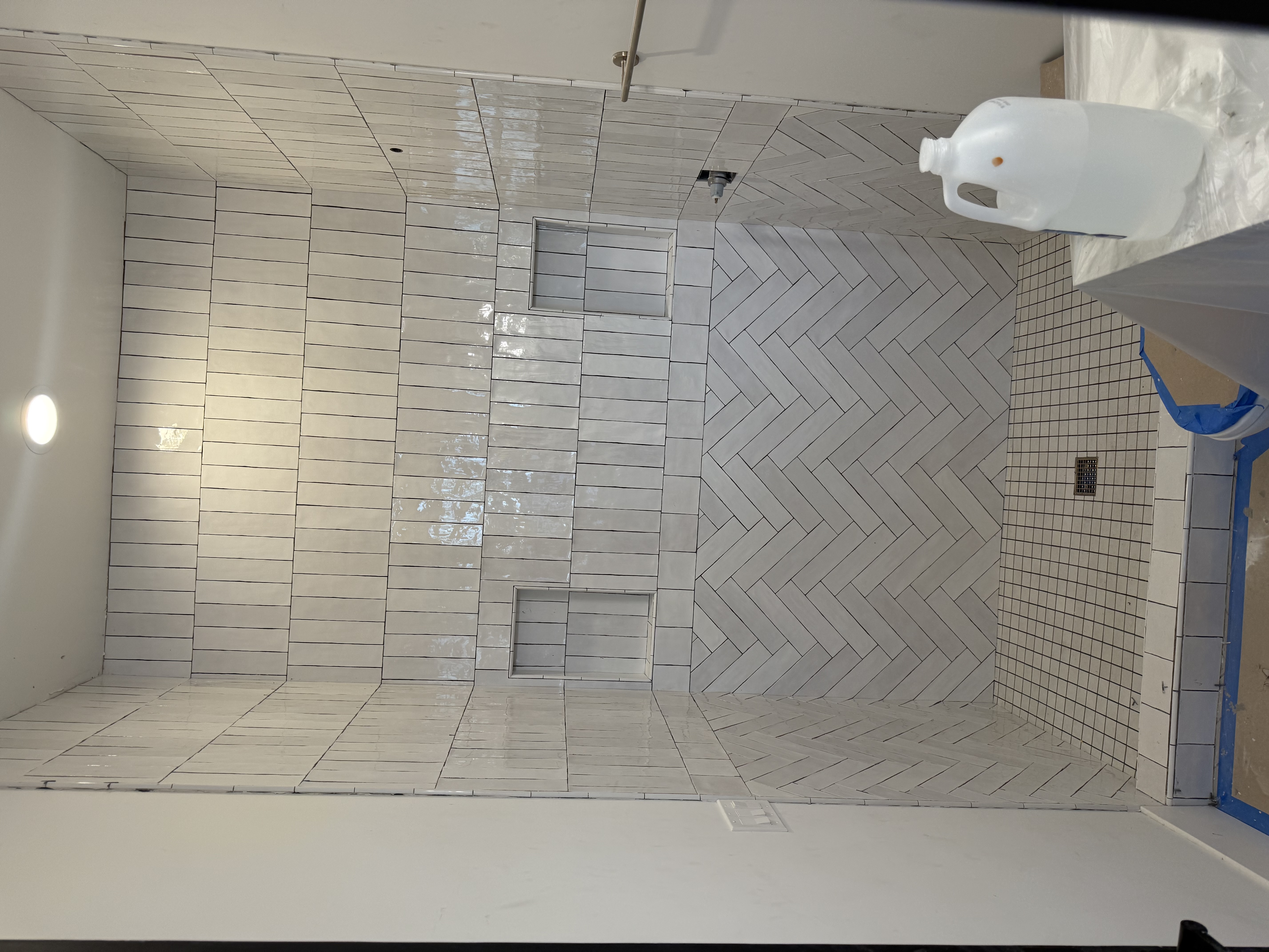 White herringbone accent wall shower with dual niches by Level Up Tile