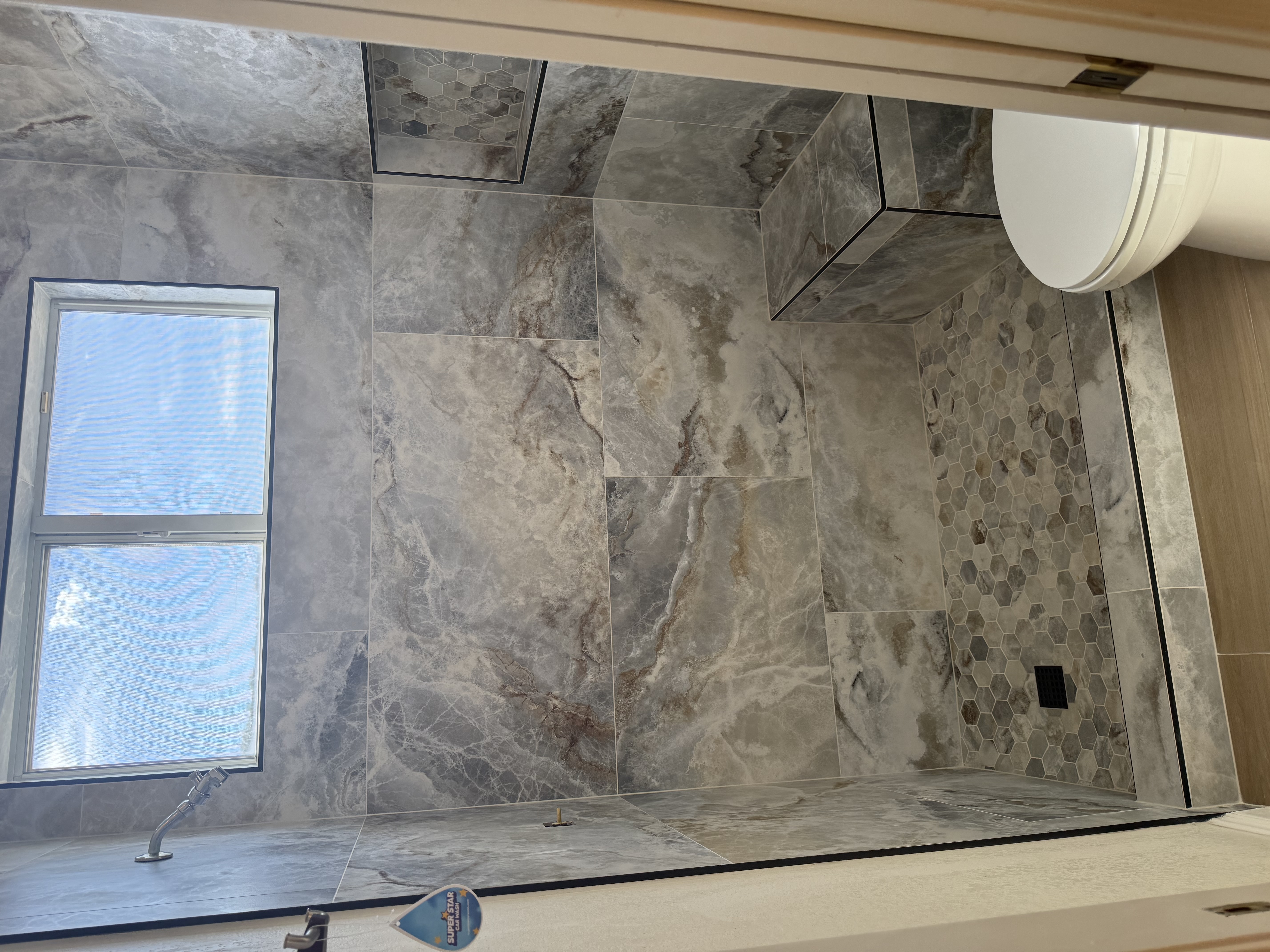 Gray marble shower with hexagonal niches installed by Level Up Tile in Peoria AZ