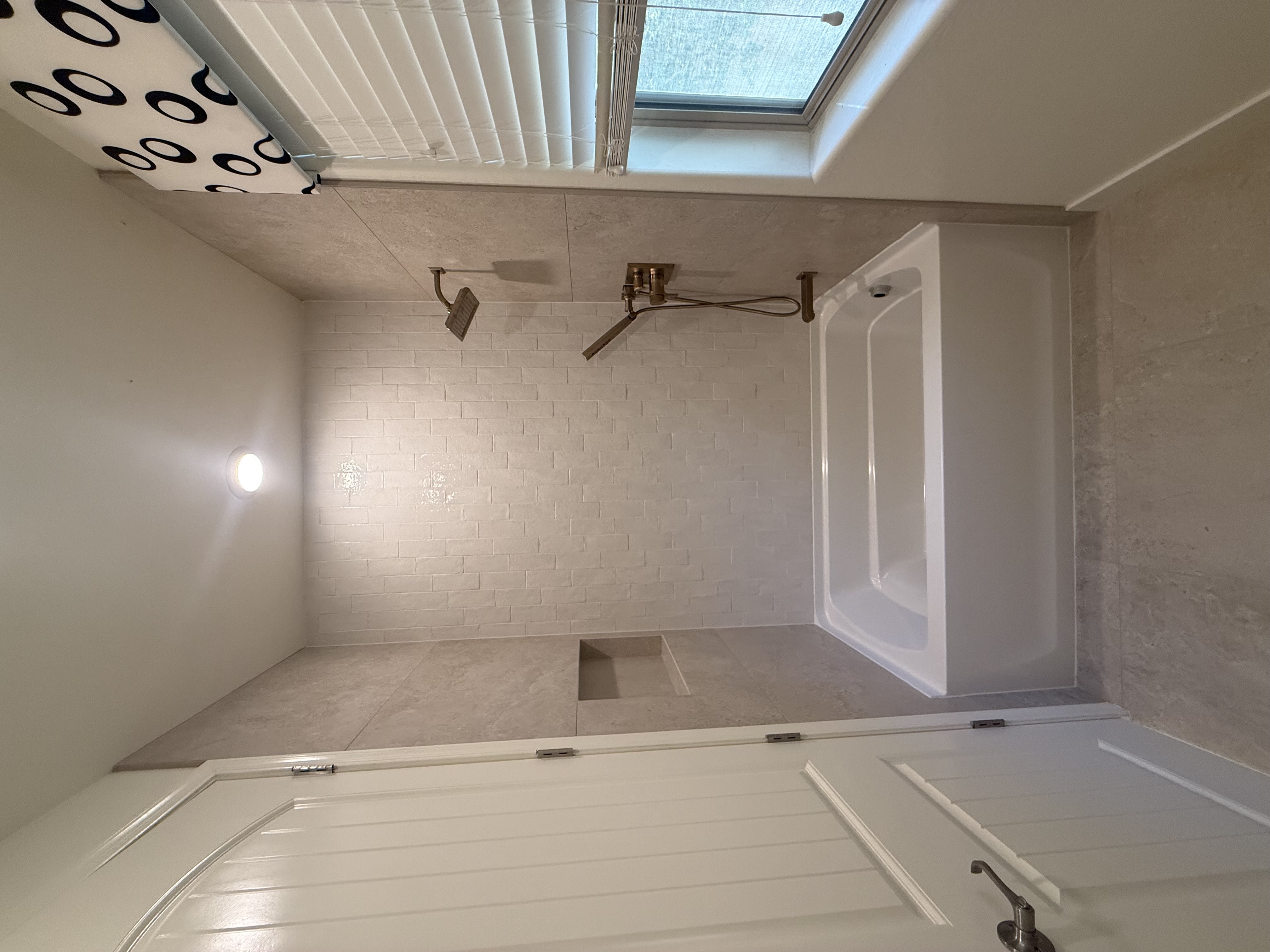 White marble shower with skylight installed by Level Up Tile